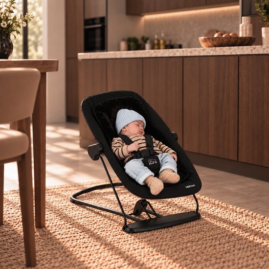 Slapende baby met blauw mutsje in een zwarte Deryan bouncer op een kleed. De bouncer is bevestigd aan een donkerbruin frame.