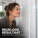 Een vrouw kijkt naar glanzende witte tegels in een badkamer.