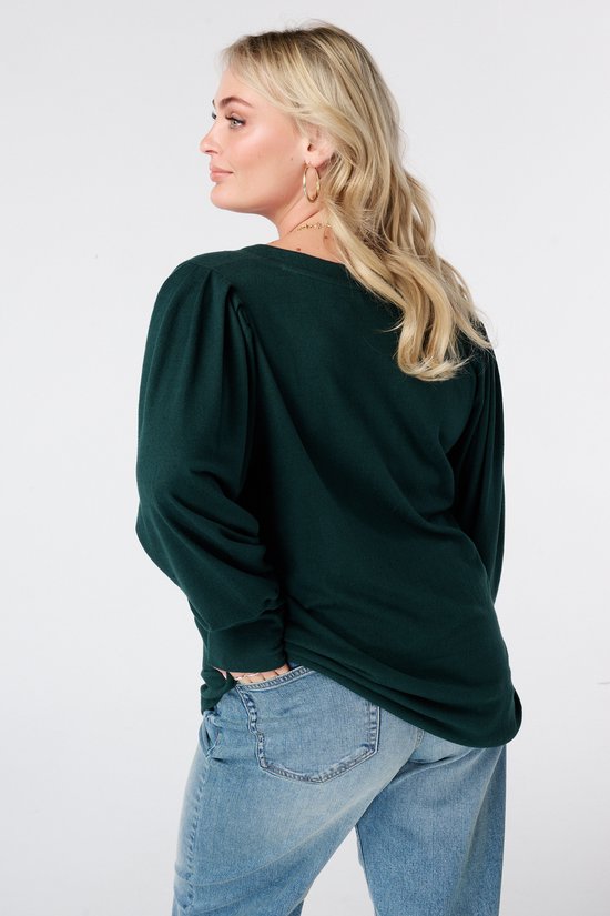 Model van achteren in donkergroene top met pofmouwen en jeans.