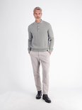 Model draagt een grijze polo met textuur en verticale strepen, gecombineerd met een beige broek en donkere schoenen.