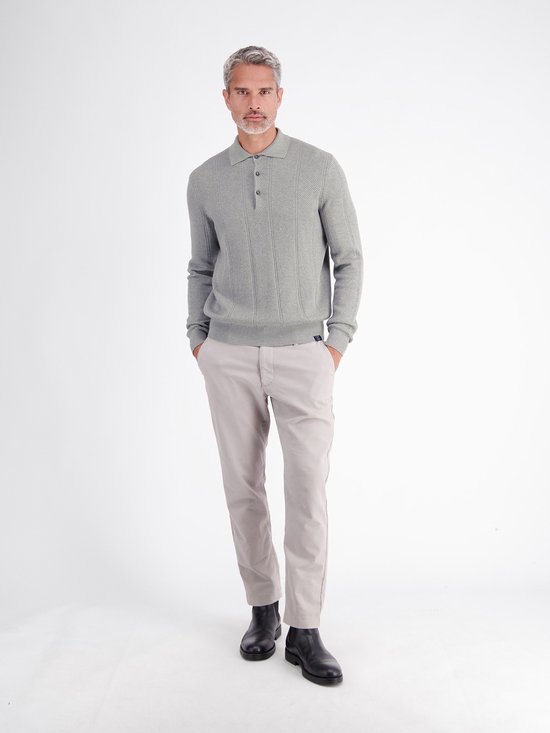 Model draagt een grijze polo met textuur en verticale strepen, gecombineerd met een beige broek en donkere schoenen.