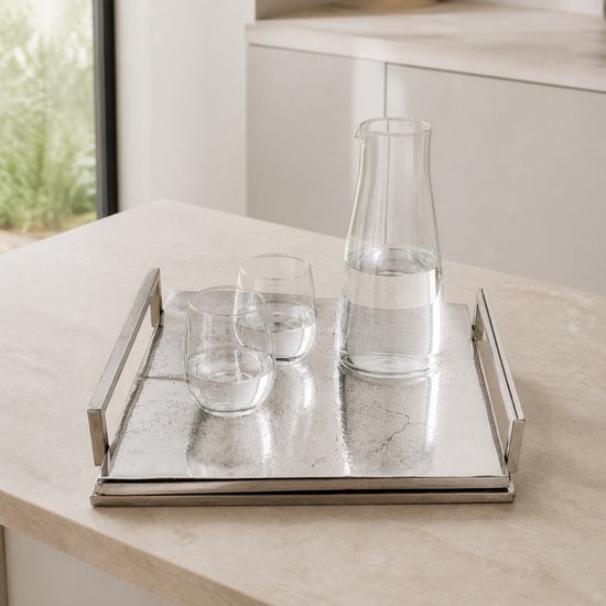 Een vierkant, zilverkleurig dienblad met handgrepen, met daarop een karaf en twee glazen gevuld met water.