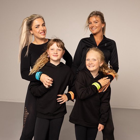 Twee vrouwen en twee kinderen in zwarte sportkleding dragen felgekleurde, reflecterende BEE-SAFE armbanden.