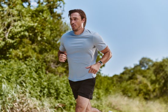 Man in sportkleding rent buiten met een Fitbit Edge aan zijn pols.