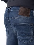 Close-up van de achterkant van een donkerblauwe jeans met een bruin leren label.