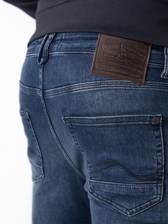 Close-up van de achterkant van een donkerblauwe jeans met een bruin leren label.