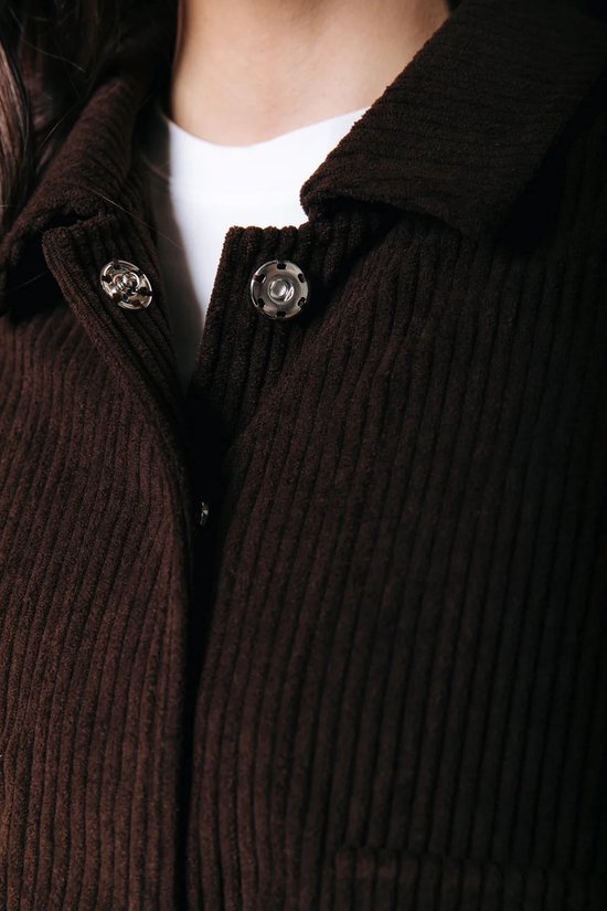 Bruine corduroy jas met zilverkleurige drukknoopsluiting.