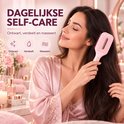 Vrouw ontwart en masseert haar haar met een roze elektrische borstel.