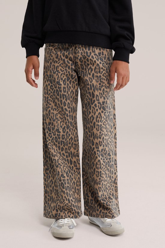 Wide leg jeans met luipaardprint, gecombineerd met een zwarte trui en zilverkleurige sneakers.