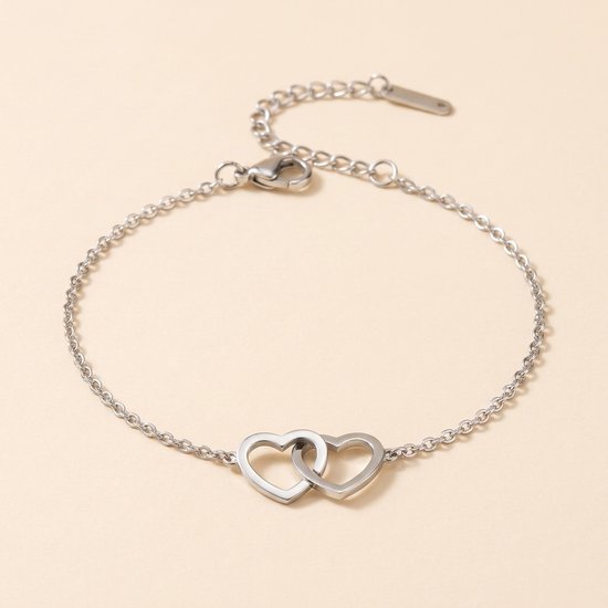 Zilverkleurige schakelarmband met twee in elkaar grijpende hartjes, gemaakt van roestvrij staal.