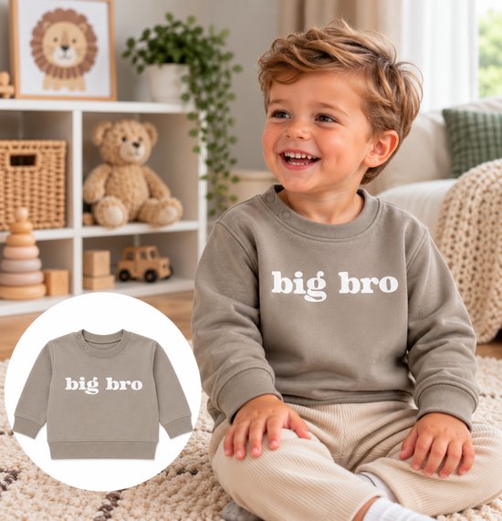 Peuter draagt beige trui met ronde hals en witte 'big bro' tekst op de borst, zittend op een tapijt.