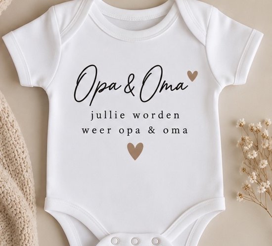 Witte babyromper met zwarte tekst 'Opa & Oma jullie worden weer opa & oma' en twee beige hartjes.