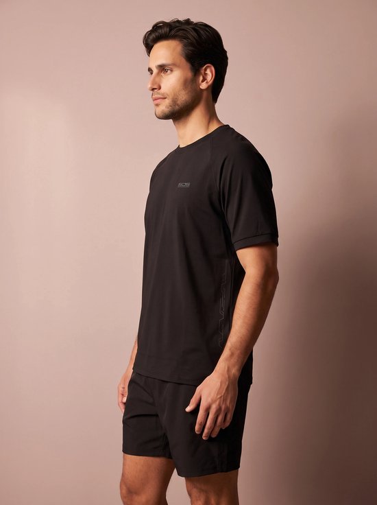 Man in profiel, draagt zwart sportshirt met logo op de borst en zwarte sportshort.