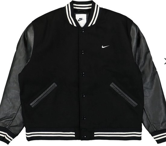 Zwarte Nike varsity jack met lederen mouwen, drukknoopsluiting en wit Nike-logo op de borst.