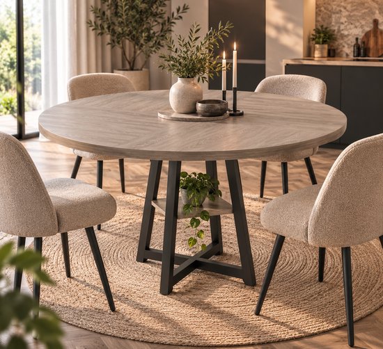 Ronde eettafel met grijs houten blad en zwart metalen kruisvoet. Een plant staat op het opbergvak. Vier beige eetkamerstoelen eromheen.