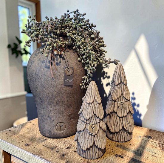 Donkerbruine, getailleerde pot met een bosje groene bessen en twee decoratieve kerstbomen met bruine accenten.