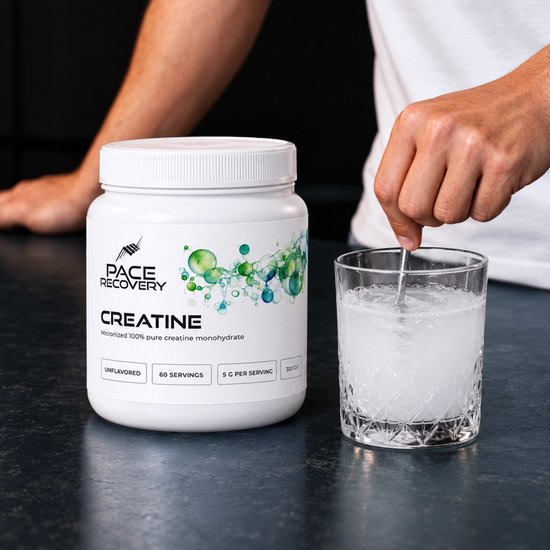 Hand roert Pace Recovery creatinepoeder in een glas water naast de witte pot op een donkere ondergrond.