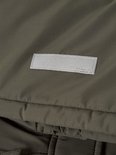 Close-up van een olijfgroene jas met een reflecterend label waarop 'name it' staat.