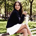 Vrouw op een bankje in het park houdt een beige VANN drinkfles van 750 ml met rietje vast.