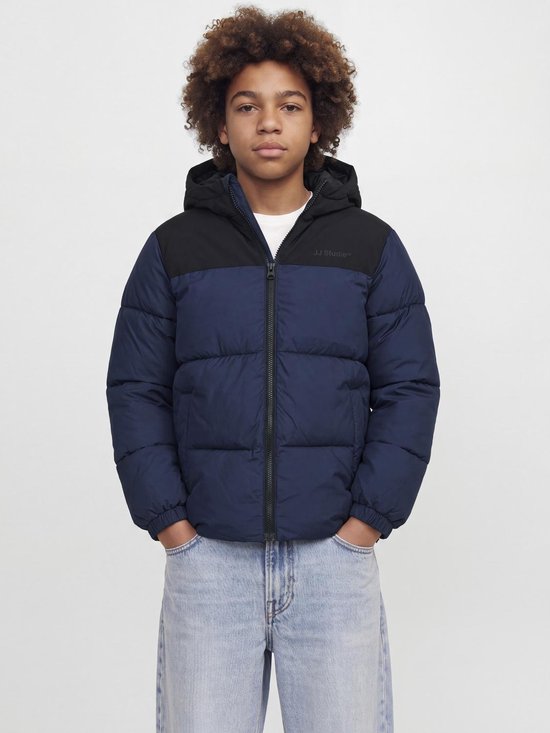 Model draagt een tweekleurige gewatteerde jas met 'JJ Studio' logo op de borst.