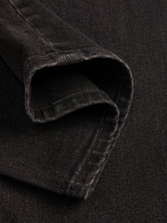 Close-up van de omgeslagen zwarte denim zoom met stikseldetails.