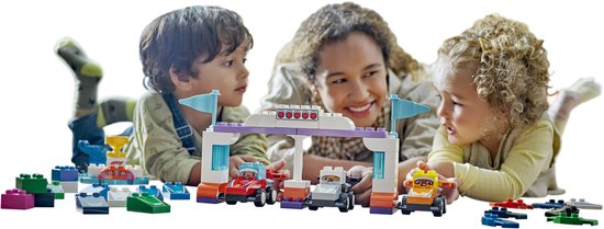 Une femme et deux enfants jouent avec une piste de course LEGO Duplo.