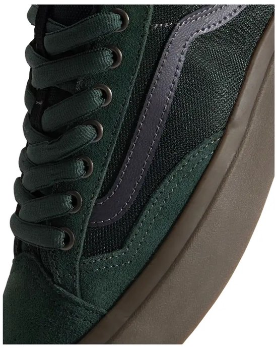 Detail van een groene Vans Old Skool sneaker, met focus op de veters, het donkergrijze Vans-logo en de donkerbruine zool.