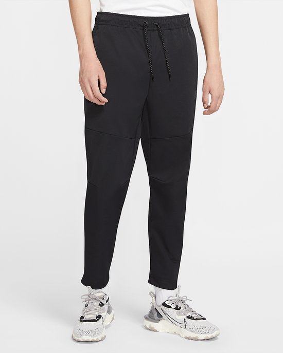 Een man in een zwarte Nike trainingsbroek met trekkoord en ritszakken.