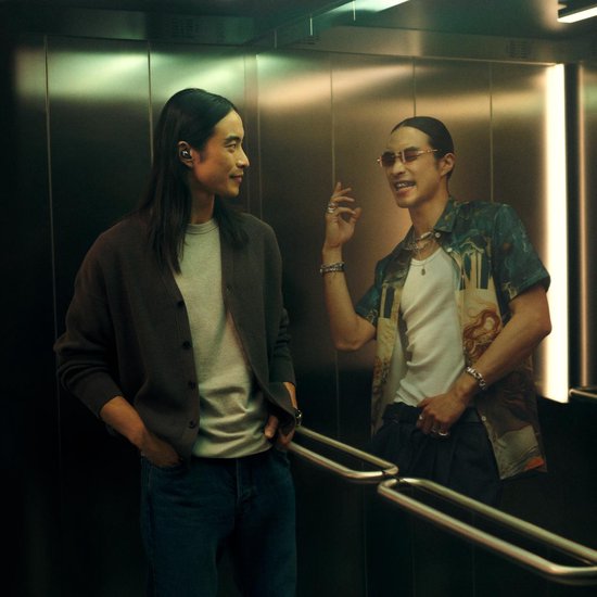 Twee mannen in lift, één met oordopjes, kijken elkaar aan.