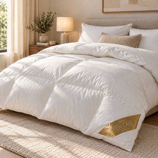 Wit donzen dekbed van Ten Cate op een opgemaakt bed met beige kussens en een neutrale slaapkamerinrichting.