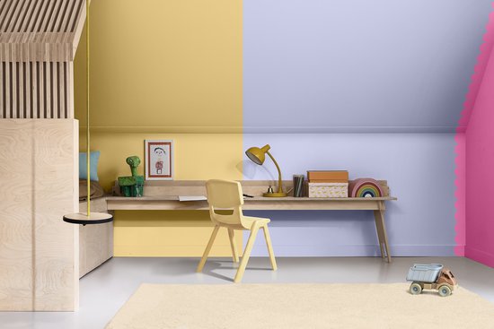 Een kinderkamer met een bureau onder een geel en paars geverfde muur. Pastelkleurige inrichting met houten accenten.