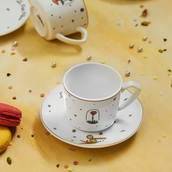 Detailopname van een Le Petit Prince-espressokopje op een schotel, versierd met een roos in een glazen stolp.