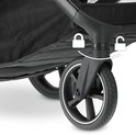Detail van de voorwielophanging en het frame van een beige kinderwagen.