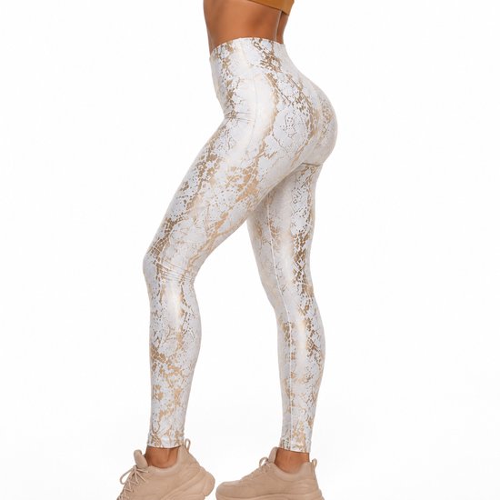 Zij-aanzicht van een witte legging met gouden slangenprint. Het model draagt beige sportschoenen.