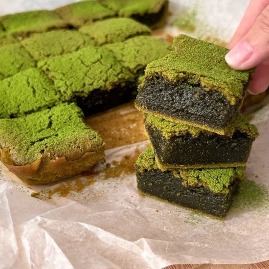 Gestapelde matcha brownies bestrooid met groene matcha poeder.