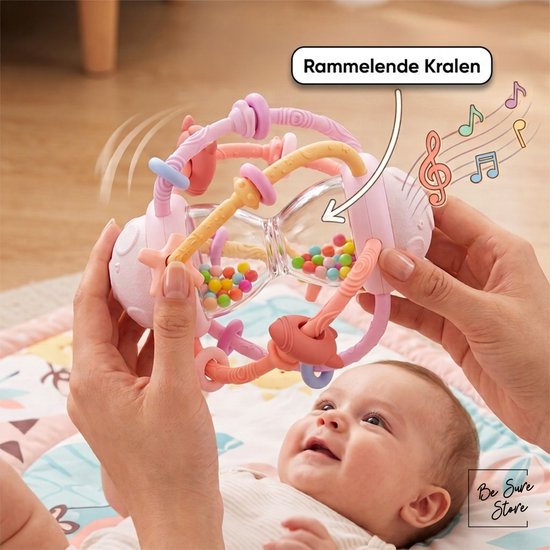 Roze, paarse en gele rammelaar in zandloper-vorm met veelkleurige kraaltjes binnenin, vastgehouden door twee handen boven een baby.