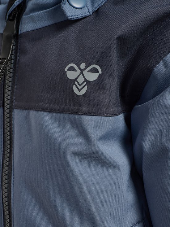 Detail van het Hummel logo op een donkerblauwe band van een blauwe kinder winterjas.