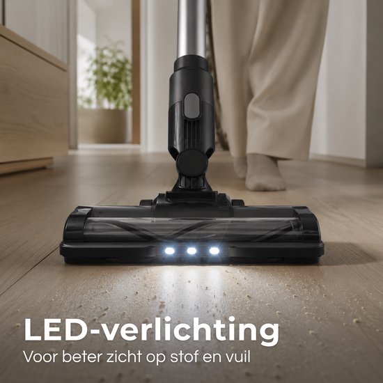 Gezichtspunt vanuit de vloer, waarbij de LED-verlichting op de zwarte steelstofzuigerkop schijnt op stof op een houten vloer. "LED-verlichting Voor beter zicht op stof en vuil".