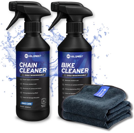 Twee zwarte spuitflessen, "Chain Cleaner" en "Bike Cleaner", met water spetters en een stapeltje donkergrijze doeken.