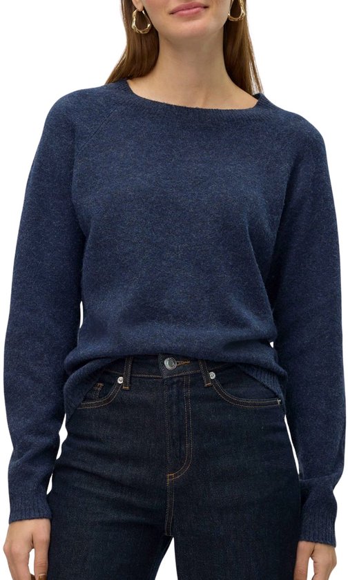 Model in donkerblauwe gebreide trui met ronde hals en jeans.