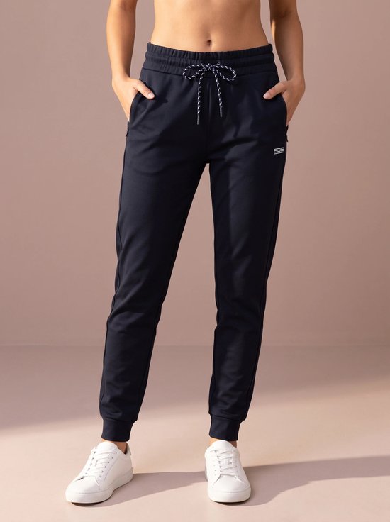 Donkerblauwe sportbroek op model, met koord, logo en handen in de zakken.