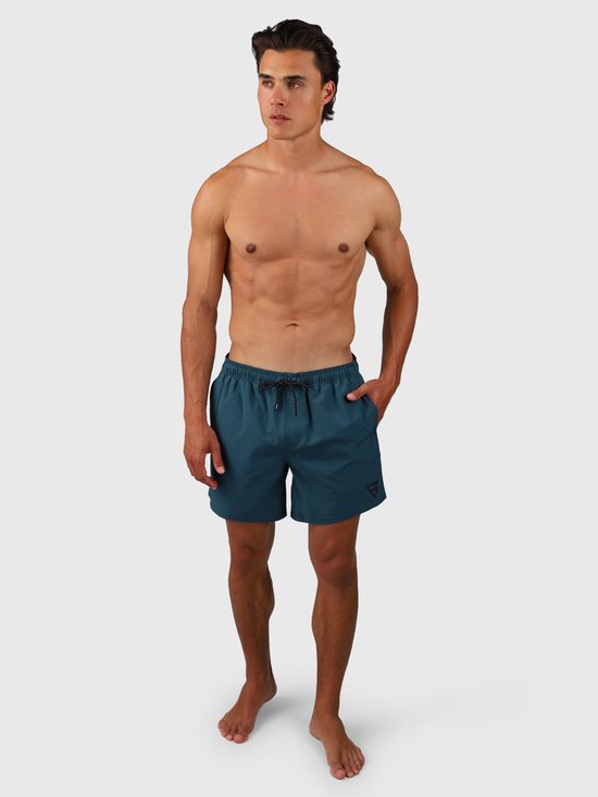 Homme portant un maillot de bain vert Fuel. Le maillot de bain a un cordon de serrage et un logo sur la jambe gauche.