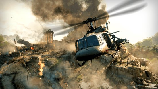 Helikopter vliegt over een verwoest dorp met rook en brand.
