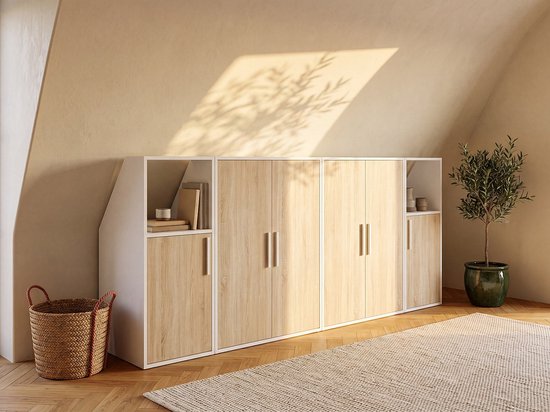Lange witte kast met naturel houten deuren onder schuin dak, nis met mand rechts.