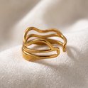 Gouden ring met open uiteinden en golvende, overlappende lijnen, liggend op een witte stof.