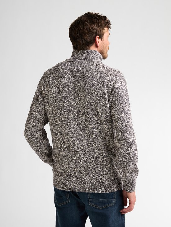 Man van achteren gezien met gemêleerde blauw-witte trui met rits en donkere spijkerbroek.