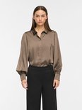 Taupe satijnen blouse met pofmouwen en knoopjes, gedragen door een model.