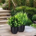 Twee kunstplanten in zwarte potten op een houten tafel in de tuin.