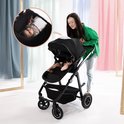 Grijze kinderwagen met baby erin, een vrouw duwt de kinderwagen.