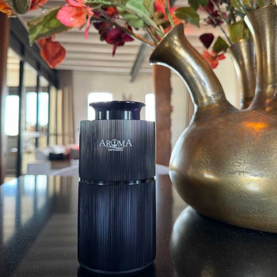 Zwarte, geribbelde Aroma diffuser naast een antieke vaas met bloemen.